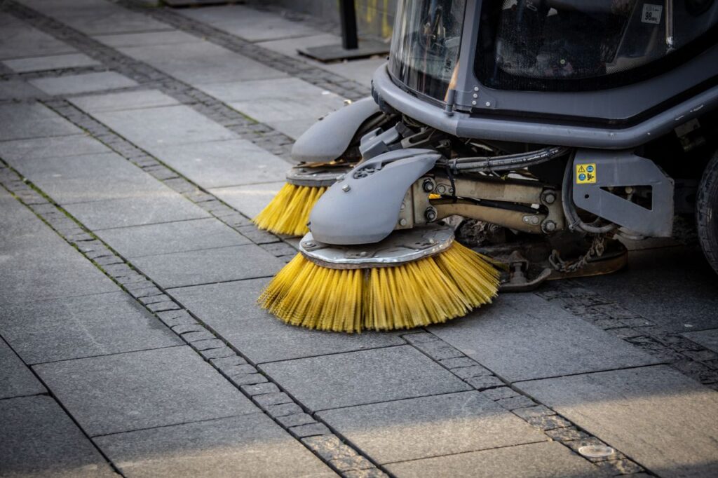 pexels photo 14642696 Close-up view of a road sweeper's yellow brushes on a paved street.